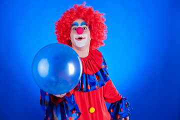 Happy clown with balloon on blue background