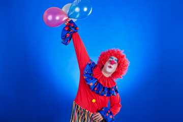 Happy clown with balloon on blue background