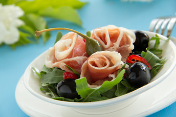 Salad with arugula, prosciutto and olives.