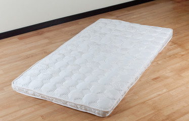 A thin mattress on wooden floor
