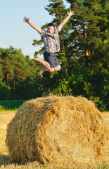 Naklejka na ściany i meble Young man jumping on a haystack