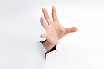 Fotobehang Female hand reaching through torn paper sheet © George Dolgikh