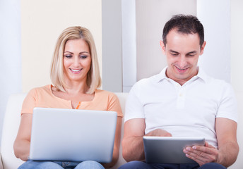 Mid-adult Couple Using Laptop And Digital Tablet