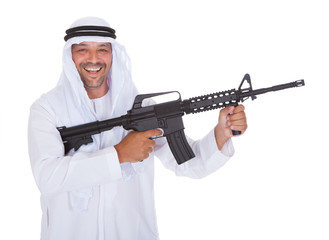 Man holding rifle while standing against white background