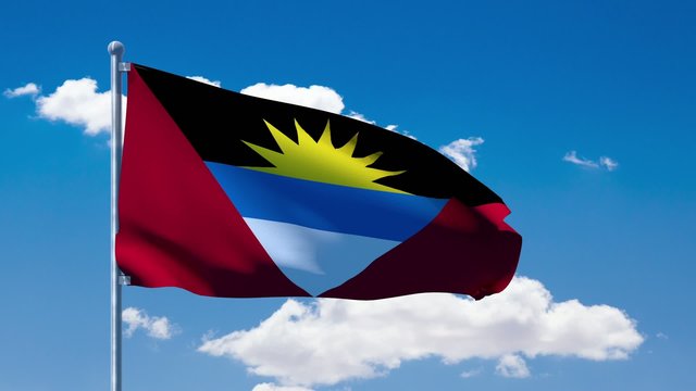 Antigua and Barbuda flag waving over a blue cloudy sky