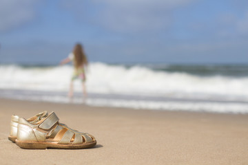 Girls sandals on sand at beach