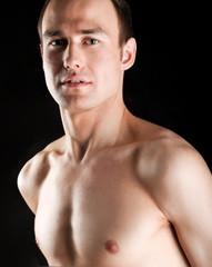 Fototapeta premium Portrait of a naked muscular man, isolated on black background
