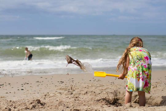 Girl in summer dress digging at beach