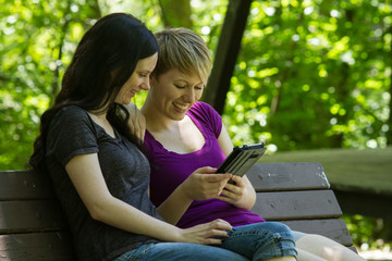 Lesbian couple using electronic tablet in park