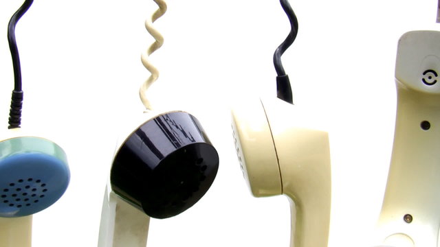 Close up of hanging rotary telephone receivers isolated