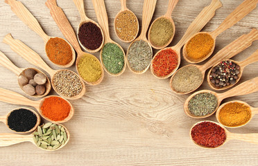 Assortment of spices in wooden spoons on wooden background