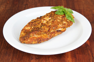 Roasted chicken fillets on white plate, on wooden background