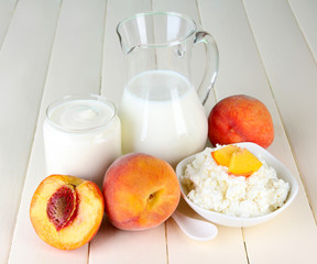 Fresh dairy products with peaches on wooden table close-up