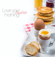 Fresh breakfast with eggs, pancakes, raspberry jam and juice
