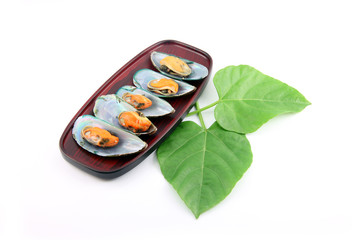 Mussel on dish and Green leaves placed beside.