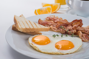 Close-up of a plate with fried eggs, bacon and toasts