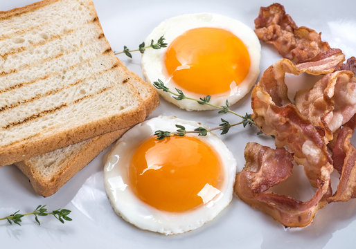 Close-up of fried eggs, bacon and toasts