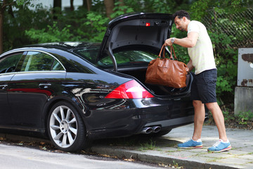 Mann packt Tasche ins Auto