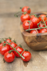 Fresh cherry tomatoes in rustic vintage wooden bowl