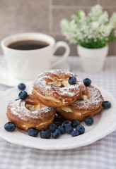 Cream puffs or choux pastry rings with blueberries on the plate