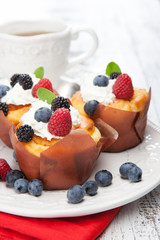 Tasty cupcakes with berries on white wooden table