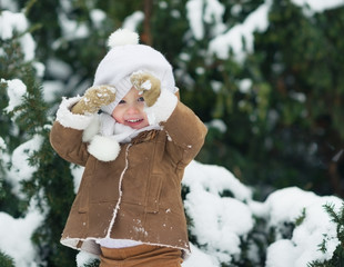 Portrait of happy baby looking out from hat in winter park