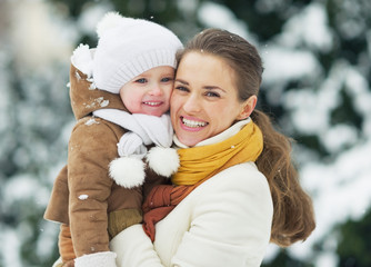 Portrait of smiling mother and baby in winter park