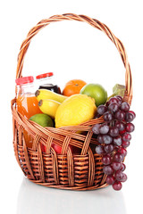 Different fruits in wicker basket with juice isolated on white