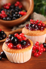 Tasty muffins with berries on wooden table