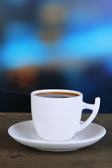 Cup of coffee on wooden table on bright background