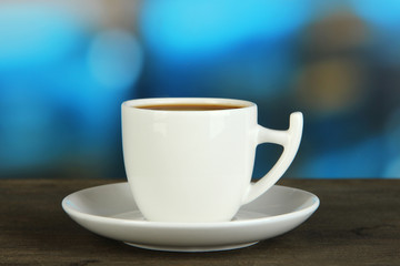 Cup of coffee on wooden table on bright background