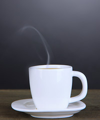 Cup of coffee on wooden table on black background