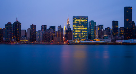 the buildings of manhattan at night in front of east river