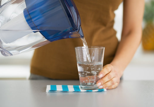 Closeup on housewife pouring water into glass