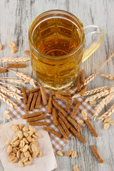 Beer in glass crunches, and nuts on napkin on wooden table
