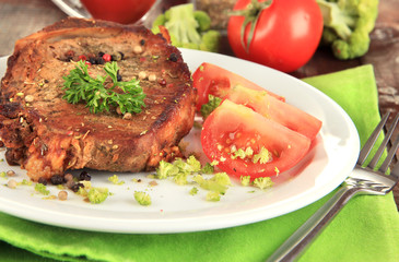 Piece of fried meat on plate on wooden table close-up