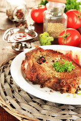 Piece of fried meat on plate on wooden table close-up