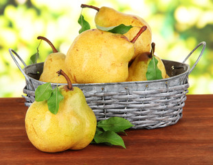 Juicy pears in wicker basket on table on bright background