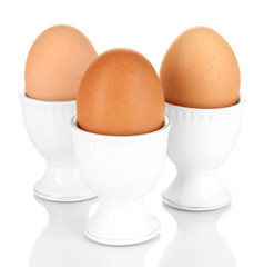 Whole boiled eggs in eggs cups isolated on white