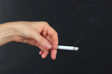 Woman hand holding cigarette with smoke, isolated on black