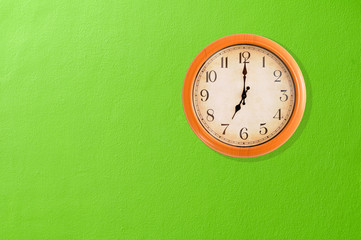 Fototapeta na wymiar Zegar pokazujący godzina siódma na zielone ściany