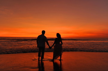 Silhouette / Shape of a bride and groom on the beach at sunset