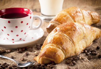 Fresh baked French croissant and dark coffee in the cup