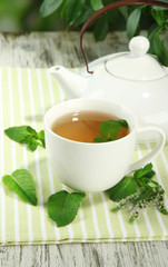 Teapot and cup of herbal tea with fresh mint flowers