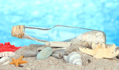 Glass of bottle with note inside on bright blue background