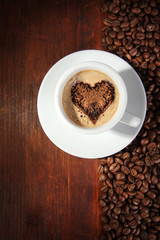 Cup of coffee with coffee beans on wooden background