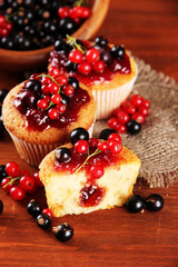 Tasty muffins with berries on wooden table