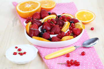 Useful fruit salad in plate on wooden table close-up