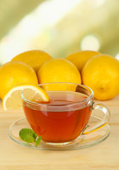 Cup of tea with lemon on table on light background