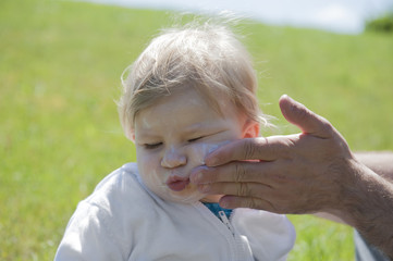 Baby getting suncream on her face , in the garden © aldegonde le compte